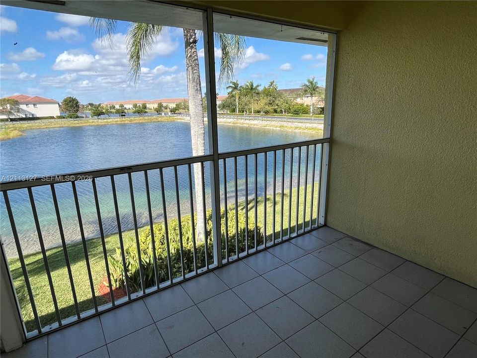 Screened-in balcony featuring tile flooring and metal railing overlooking a pond