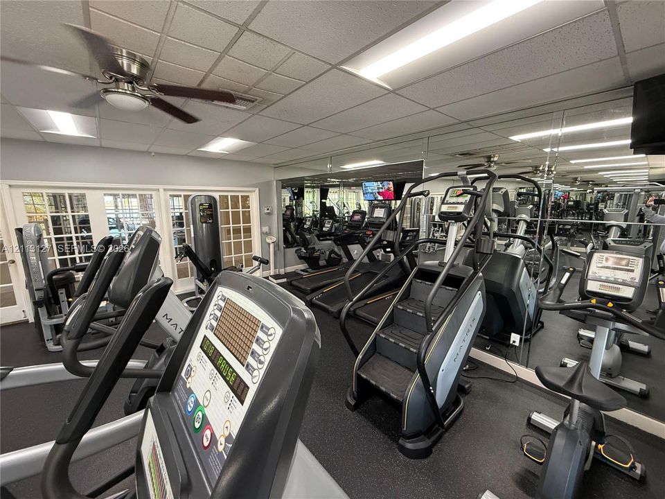 Fitness center featuring wall-to-wall mirrors, recessed lighting, ceiling fan, and French-style glass pane doors