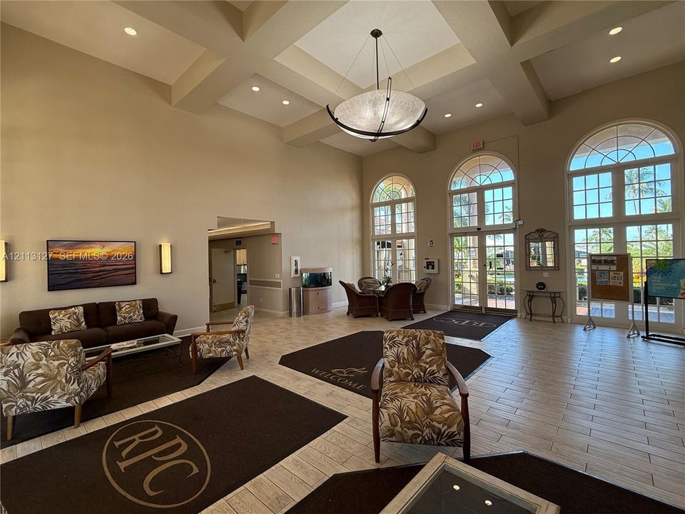 Lobby featuring vaulted coffered ceilings, expansive arched windows, tile flooring, recessed lighting, and a prominent central pendant light fixture