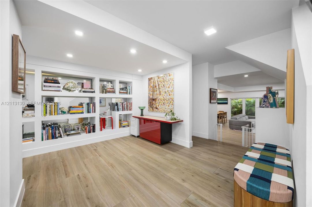 Interior space featuring wood-finish flooring, recessed lighting, and expansive built-in wall shelving with display niches