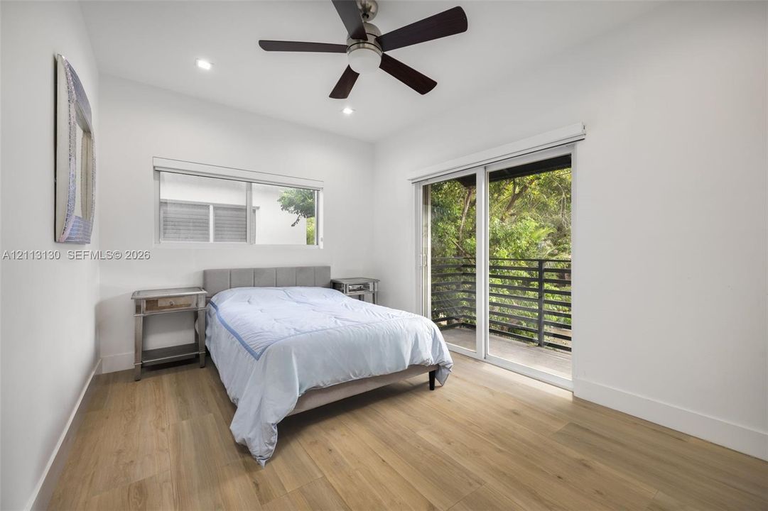 Wood-finish flooring, recessed lighting, brushed nickel ceiling fan, sliding glass door, and exterior balcony