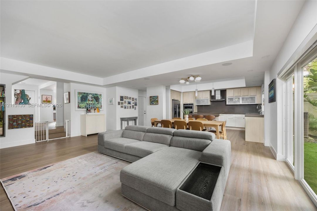Open-concept interior featuring tray ceilings, wood-finish flooring, and recessed lighting
