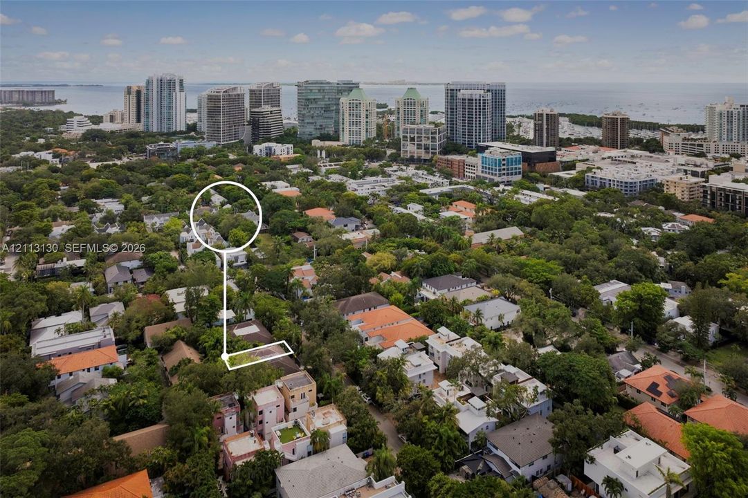 Aerial perspective of a residential lot featuring mature tree canopy, dense urban landscaping, and proximity to the coastline