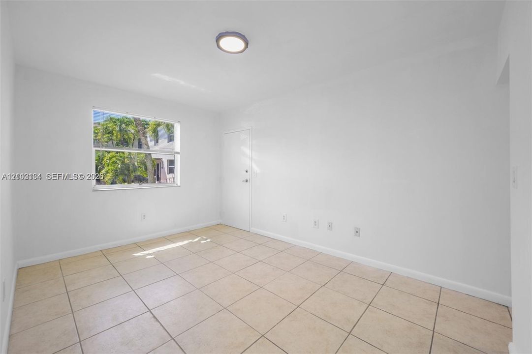 Neutral interior room featuring oversized tile flooring, a single-hung window, and a flush-mount circular ceiling fixture