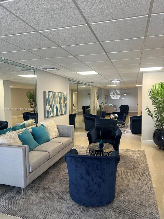 Expansive interior space featuring high-gloss tile flooring, floor-to-ceiling mirror wall panels, and recessed drop-ceiling lighting