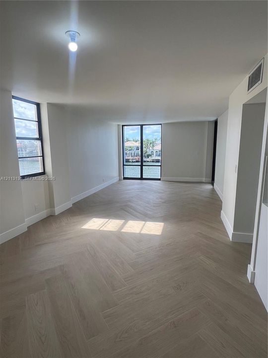 Herringbone wood-finish flooring, floor-to-ceiling windows, and water-facing exterior exposure
