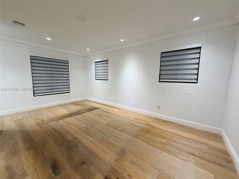 Room featuring wood-finish flooring, recessed lighting, and windows with integrated horizontal blind treatments