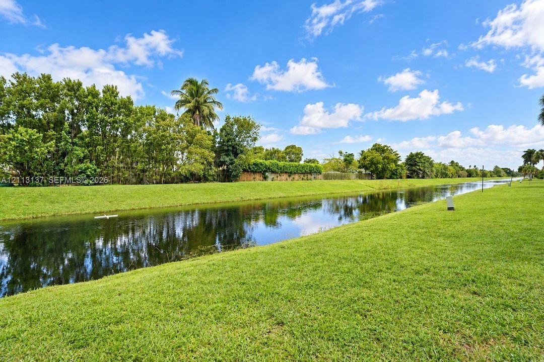 Waterfront lot featuring a grass lawn, mature trees, and palms