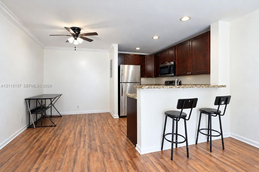 Kitchen featuring dark wood cabinetry, stone-surface breakfast bar, recessed lighting, ceiling fan, and wood-finish flooring