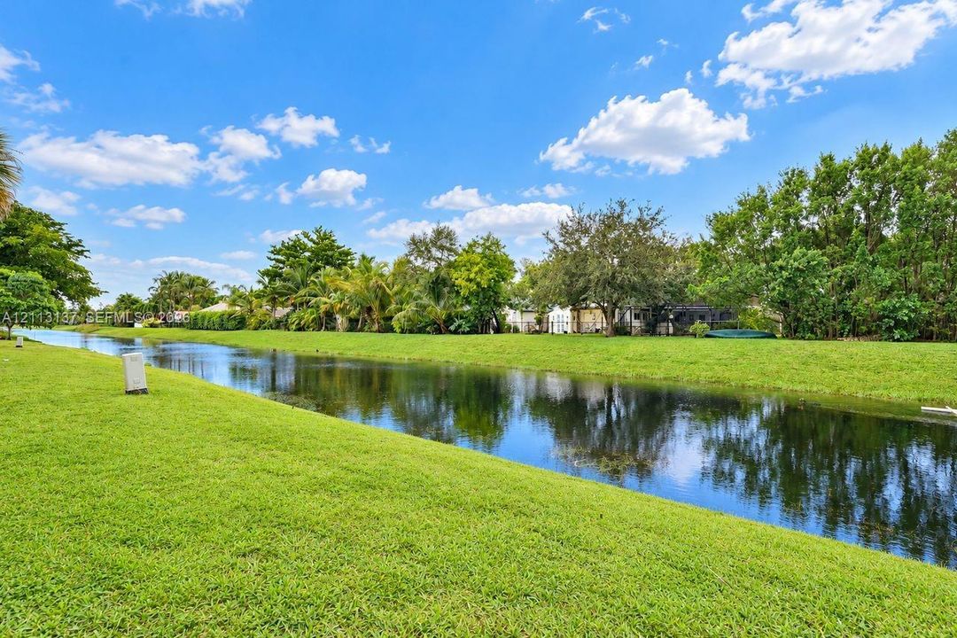 Waterfront lot featuring a grass lawn, canal frontage, and mature landscaping