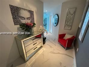 Large-format tile flooring with veined detailing, recessed lighting, and wall-mounted circular mirror