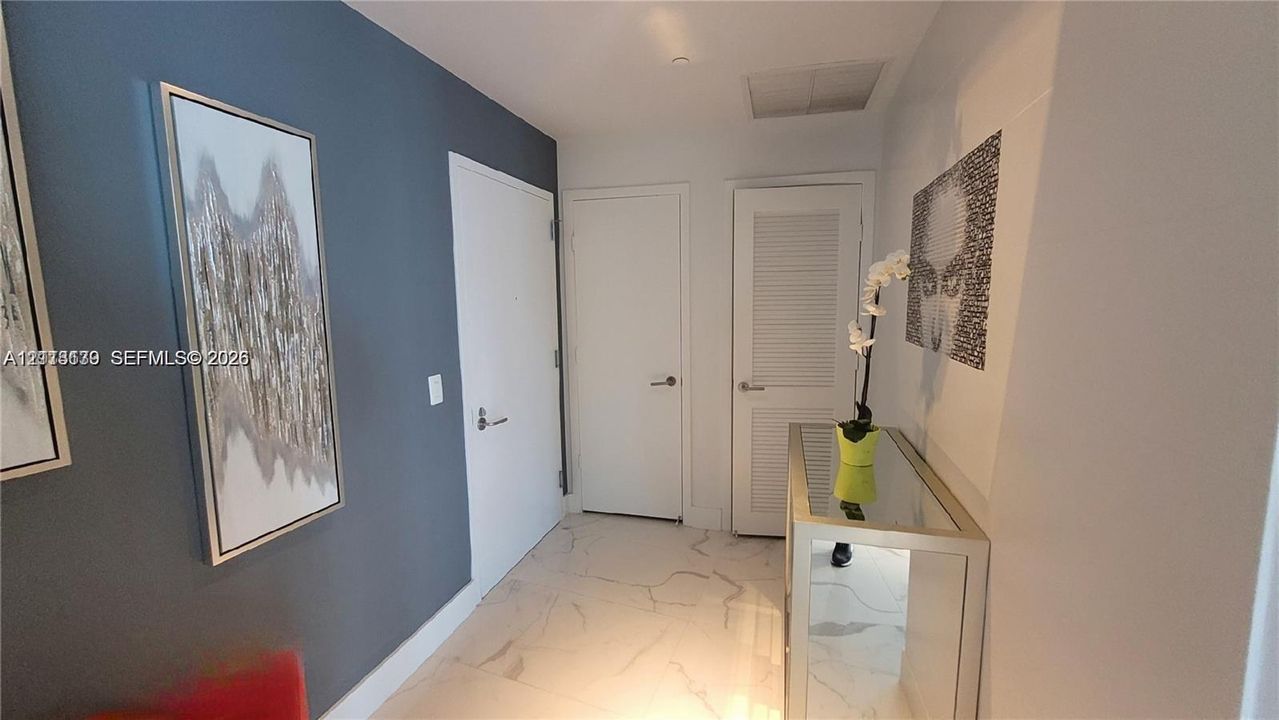 Entry featuring stone-finish flooring with neutral veining, a painted accent wall, and a louvered closet door