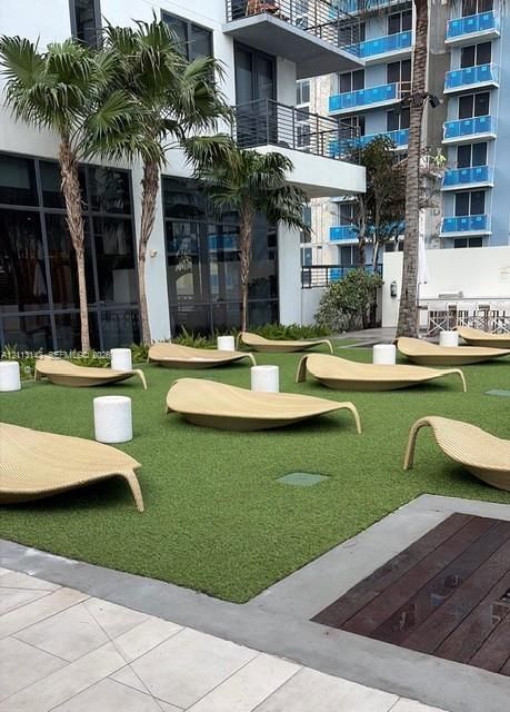 Outdoor terrace featuring synthetic turf, mature palm trees, multi-level structural balconies, and wood-inlay concrete hardscaping