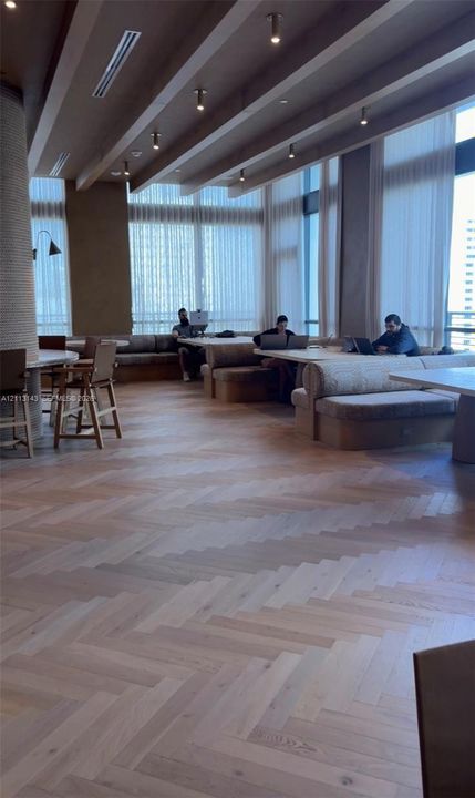 Herringbone wood-finish flooring, floor-to-ceiling windows, recessed ceiling lighting, and custom built-in bench seating