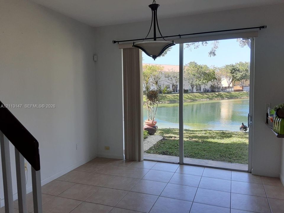 Ceramic tile flooring, multi-panel glass sliding door, metal-framed pendant lighting fixture, and stair railing with white balusters
