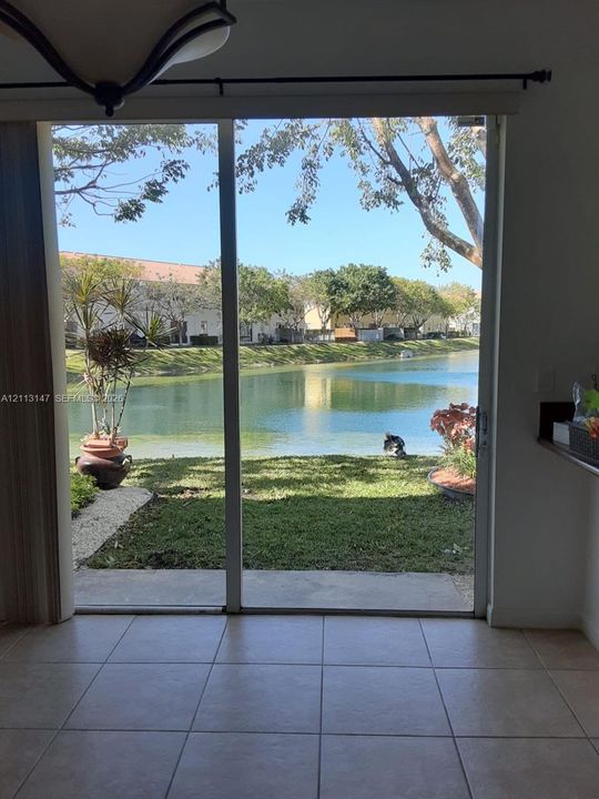 Large sliding glass doors opening to a concrete patio, grass lawn, and waterfront setting