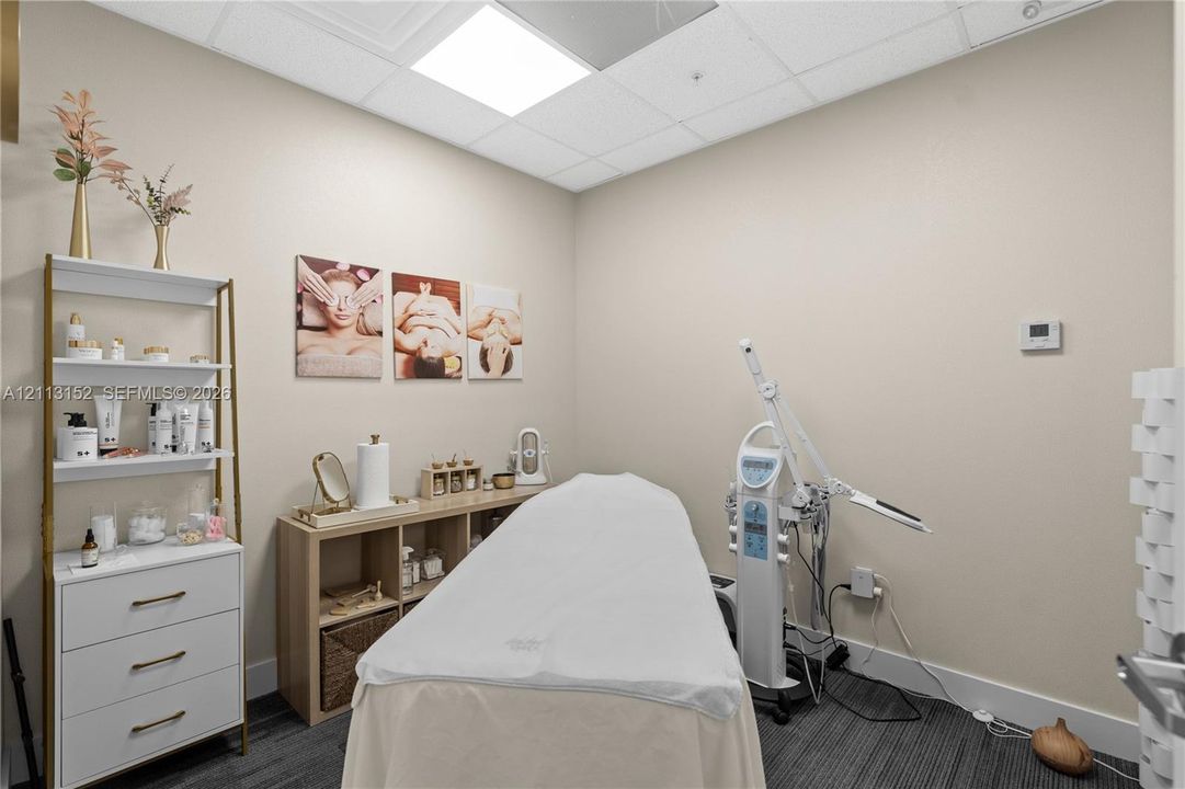 Neutral-toned interior space featuring a drop ceiling with recessed panel lighting and dark, linear-patterned carpet flooring