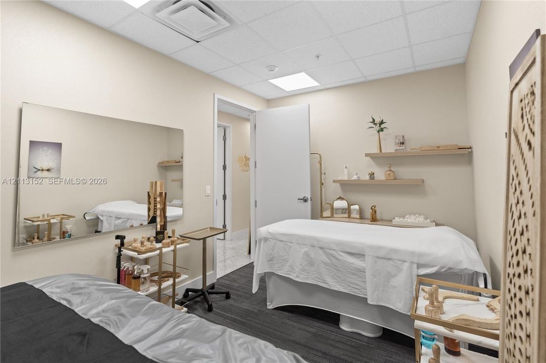 Room featuring a large wall-mounted mirror, tiered wooden wall shelving, and a drop ceiling with recessed lighting