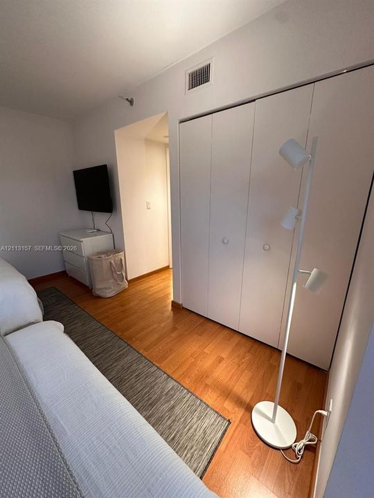 Hardwood flooring, floor-to-ceiling built-in closet with multi-panel white doors, and smooth wall finish