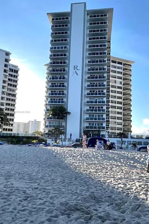 High-rise residential exterior featuring stacked private balconies, direct beach access, and expansive sand shoreline