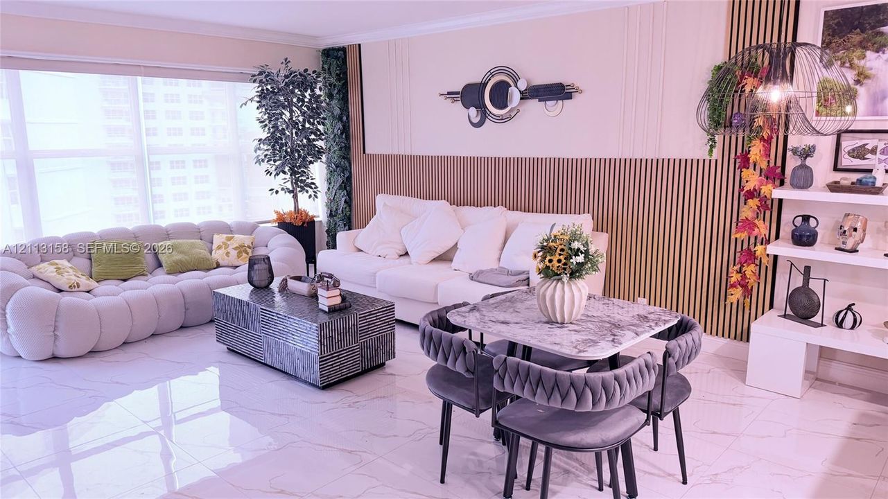 Living area featuring large-format tile flooring, vertical wood-slat accent wall detailing, floor-to-ceiling windows, and white built-in shelving