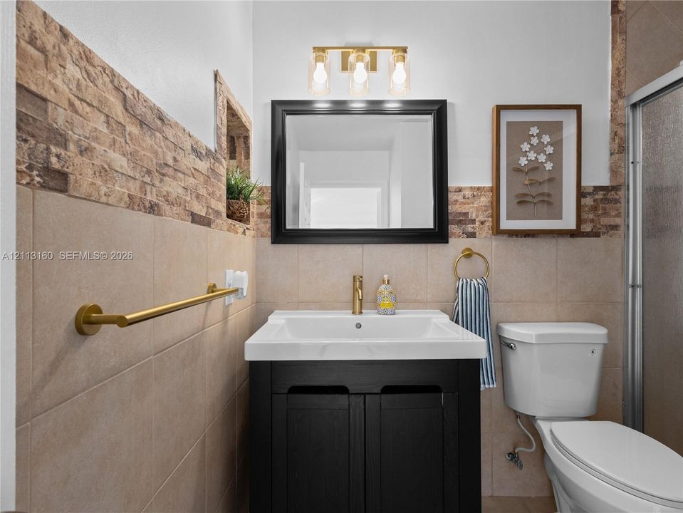 Vanity featuring a dark cabinetry base, white integrated basin, and gold-finish faucet