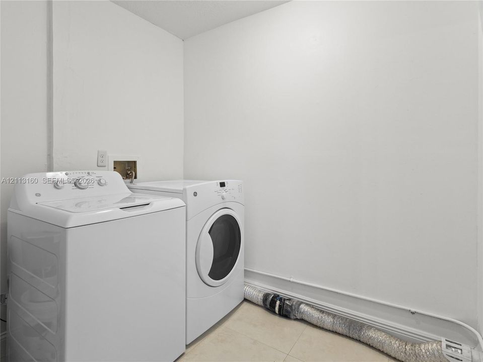 Laundry area featuring neutral-toned tile flooring and wall-mounted plumbing connections