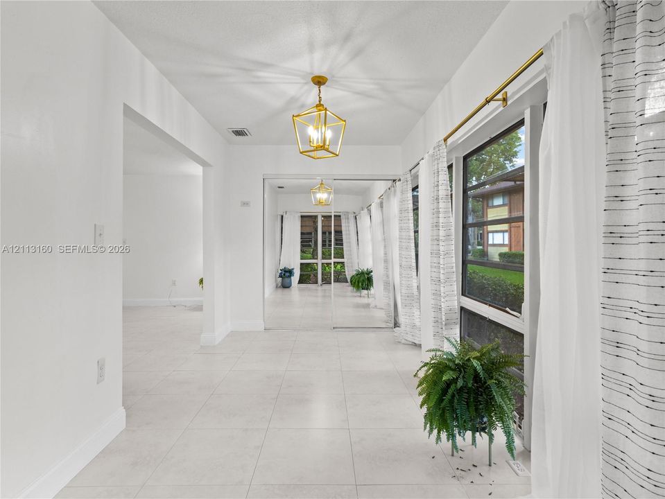 Interior space featuring large-format tile flooring, polished gold-tone geometric pendant lighting, and mirrored sliding closet doors