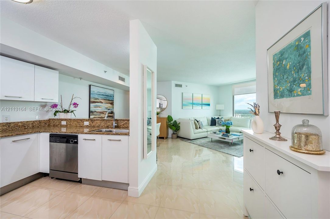 Kitchen featuring white cabinetry, stone countertops, stainless steel dishwasher, and tile flooring