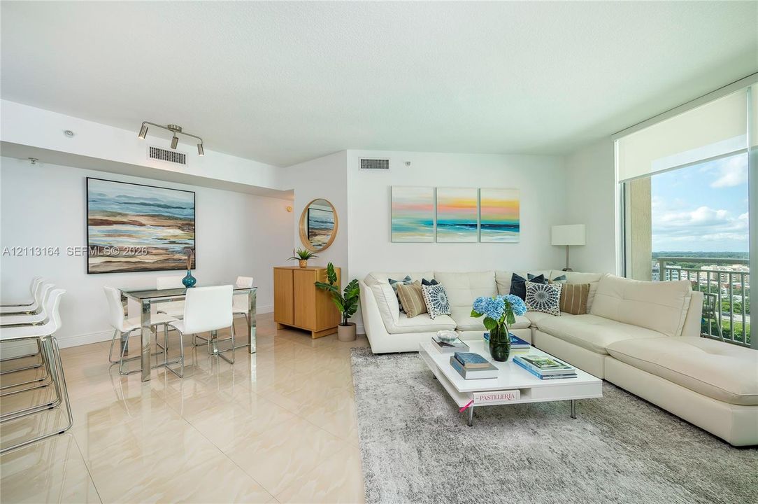 Open-concept living space featuring high-gloss tile flooring, floor-to-ceiling windows with roller shades, and integrated track lighting