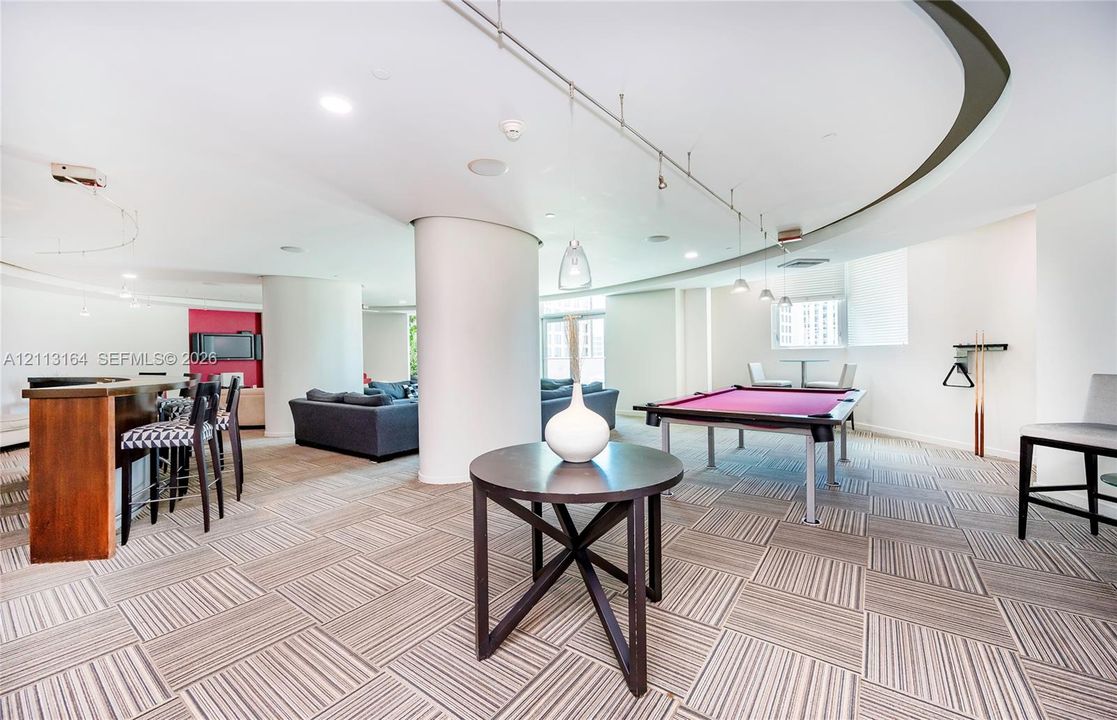 Curved architectural ceiling design, recessed lighting, track lighting, neutral tile flooring, and structural columns