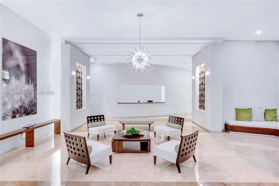 Expansive lobby featuring polished stone flooring, a starburst-style chandelier, symmetrical recessed wall niches, and built-in bench seating