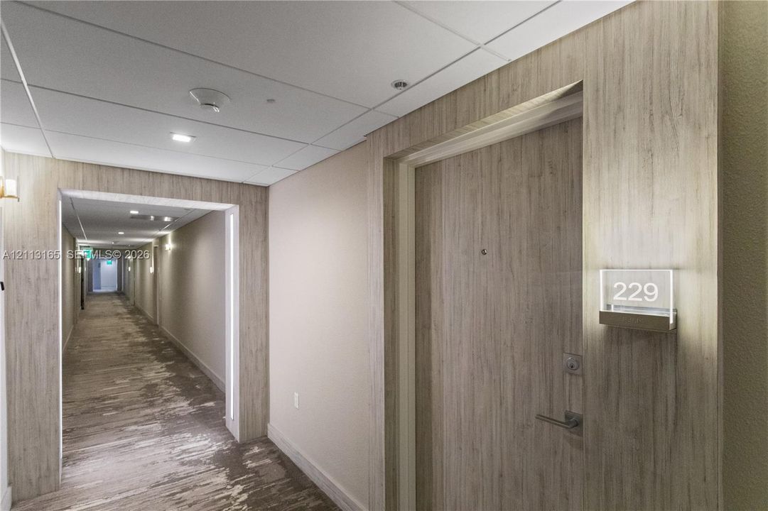 Wood-finish paneling, brushed metallic hardware, integrated door signage, and recessed ceiling lighting
