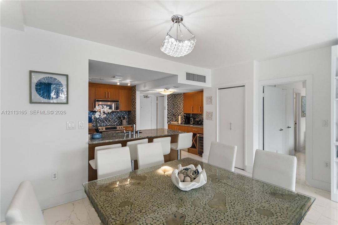 Open-concept kitchen featuring wood cabinetry, stone countertops, a breakfast bar, and decorative tile backsplash