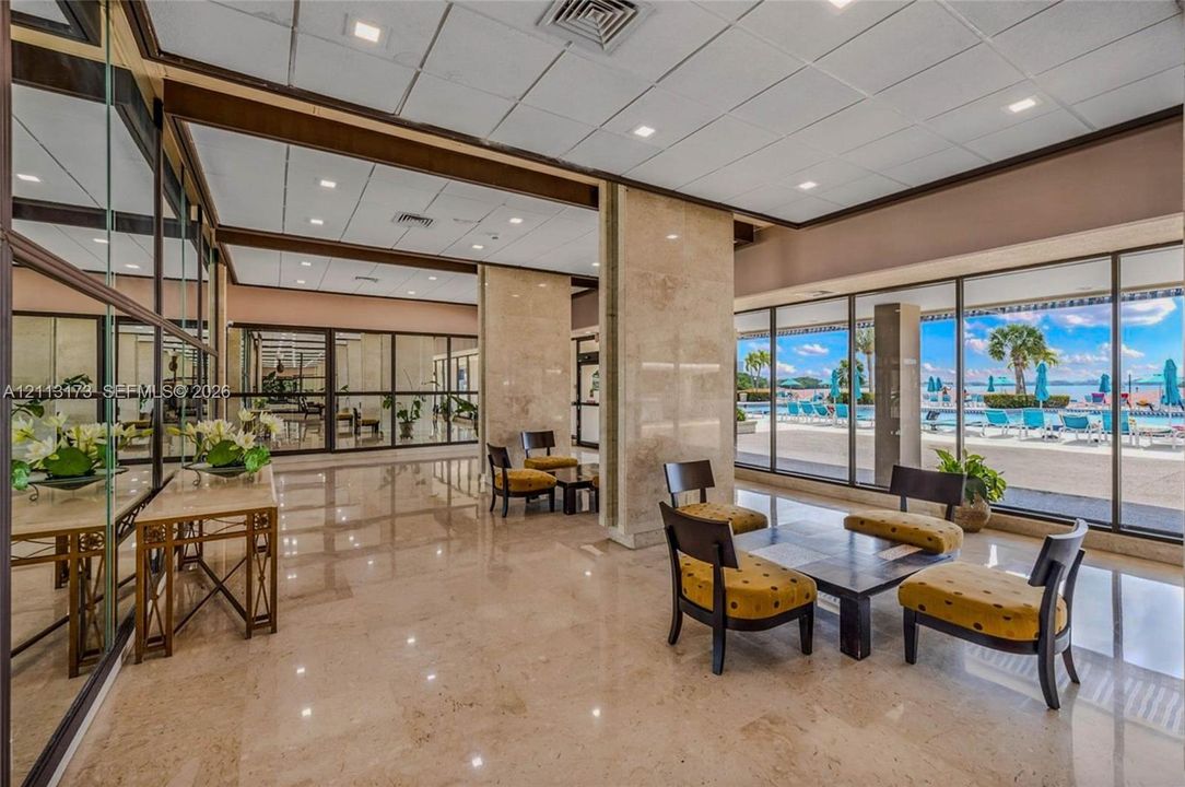 Lobby featuring polished stone flooring, floor-to-ceiling glass walls, recessed lighting, and stone-clad pillars
