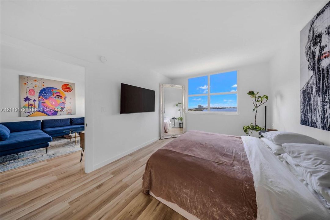 Interior space featuring wood-finish flooring, large rectangular window, and wall-mounted television