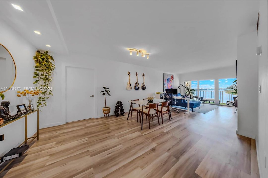 Open-concept interior featuring wood-finish flooring, recessed lighting, and expansive glass doors opening to a balcony
