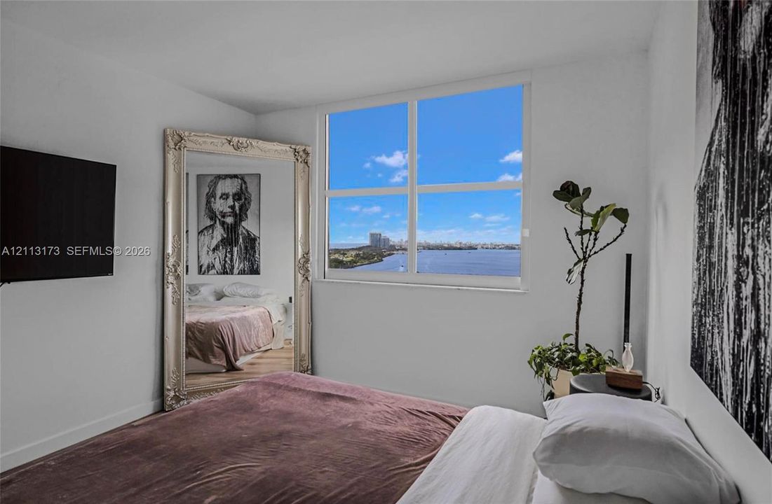 Large rectangular window featuring water and city skyline scenery, neutral wall finishes, and wood-finish flooring