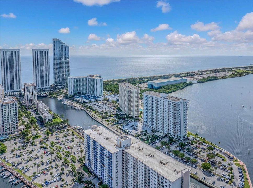 Aerial perspective of coastal high-rise development featuring waterfront proximity, deep-water canal access, paved surface parking, and proximity to the Atlantic Ocean