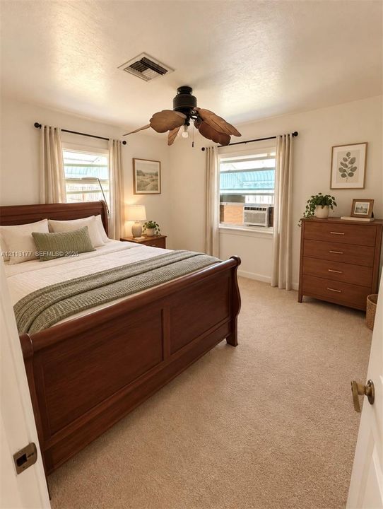 Neutral-toned carpeting, dual windows with curtain rods, and a ceiling fan with leaf-shaped blades