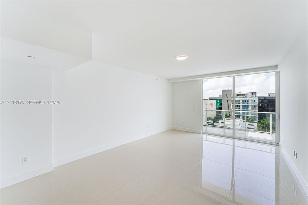 Neutral-toned tile flooring, recessed ceiling lighting, and sliding glass doors with access to an exterior balcony
