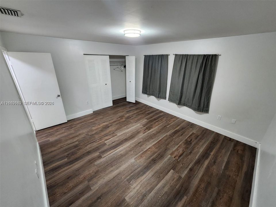 Wood-finish flooring, neutral wall tones, bi-fold closet doors, and a central flush-mount light fixture