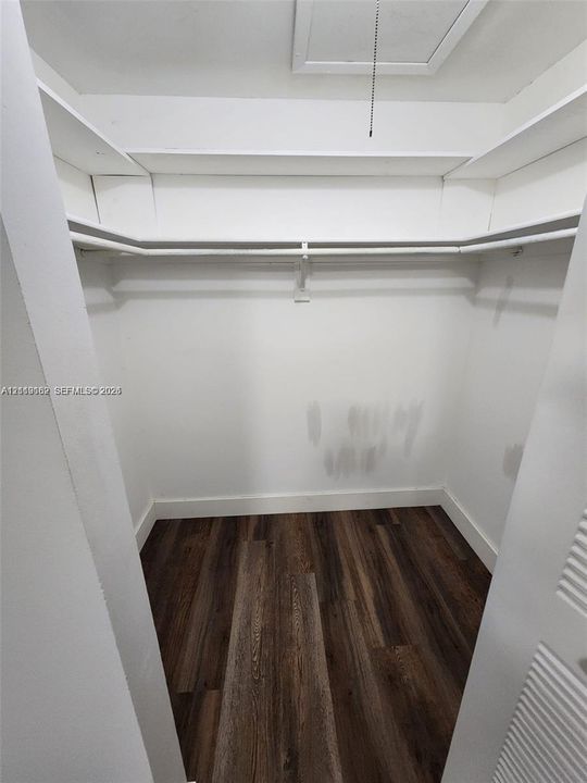 Storage closet featuring wood-finish flooring, white shelving, and an integrated hanging rod