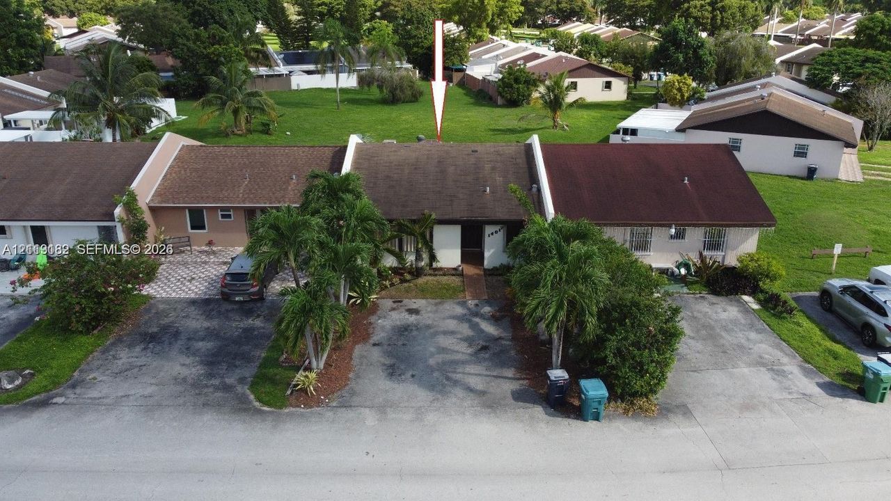 Single-story residence featuring a shingled roof, asphalt driveway, and exterior landscaping including mature palm trees
