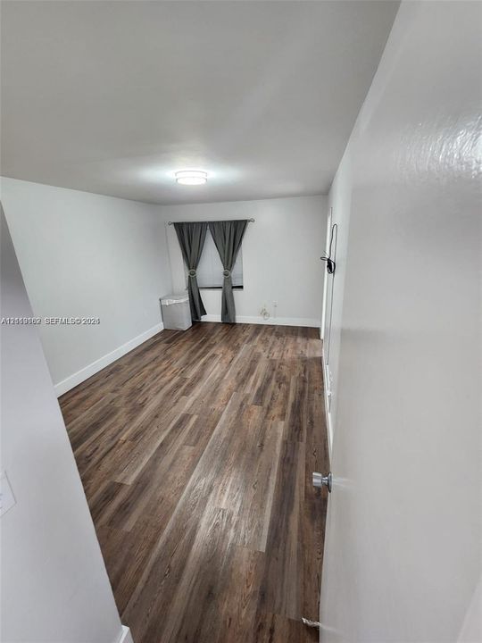 Wood-finish flooring, neutral wall tones, and a central ceiling-mounted light fixture