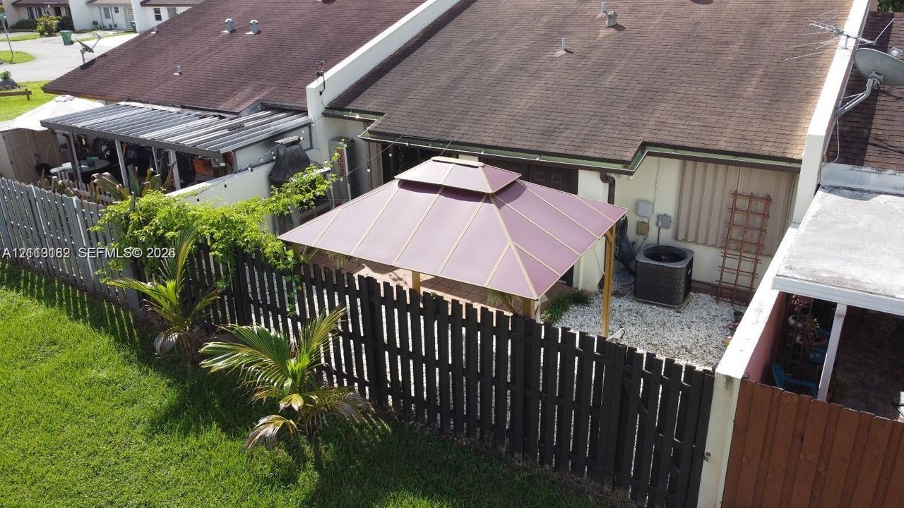 Fenced backyard featuring a permanent gazebo, gravel ground cover, and low-maintenance landscaping