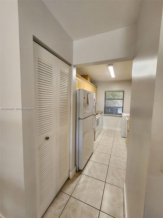 Kitchen featuring tile flooring, louvered-door closet, and window with horizontal blinds