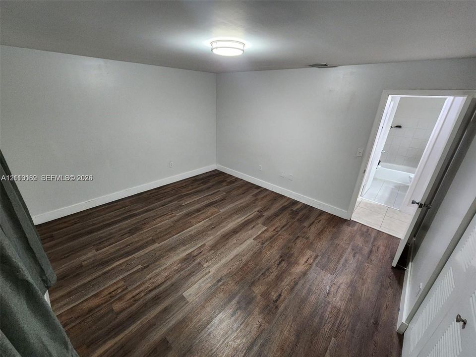 Wood-finish flooring, neutral wall paint, and flush-mount ceiling lighting