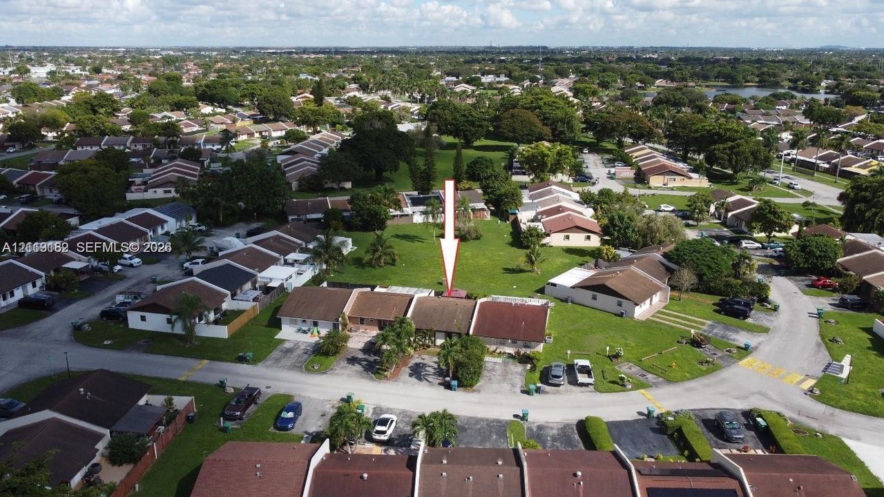 Aerial perspective of a single-story residence featuring a shingled roof, paved driveway, and extensive rear green space