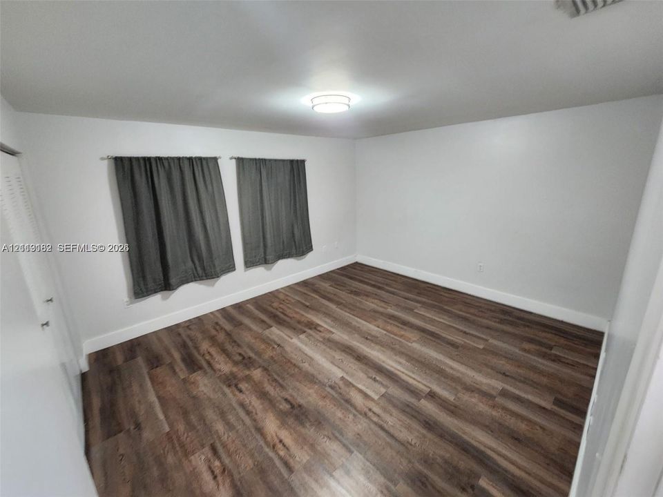 Interior space featuring wood-finish flooring, white walls, and a ceiling-mounted light fixture